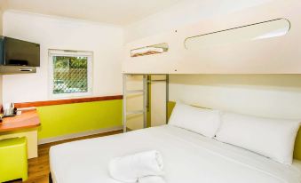 a large bed with white sheets and pillows is in a room with a green wall at Ibis Budget Windsor Brisbane