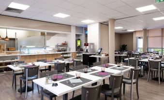 a large dining room with multiple tables and chairs arranged for a group of people to enjoy a meal together at Comfort Hotel Aeroport Lyon St Exupery