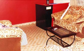 a living room with red walls , a couch , a tv , and a coffee table on a tiled floor at Coronation Hotel