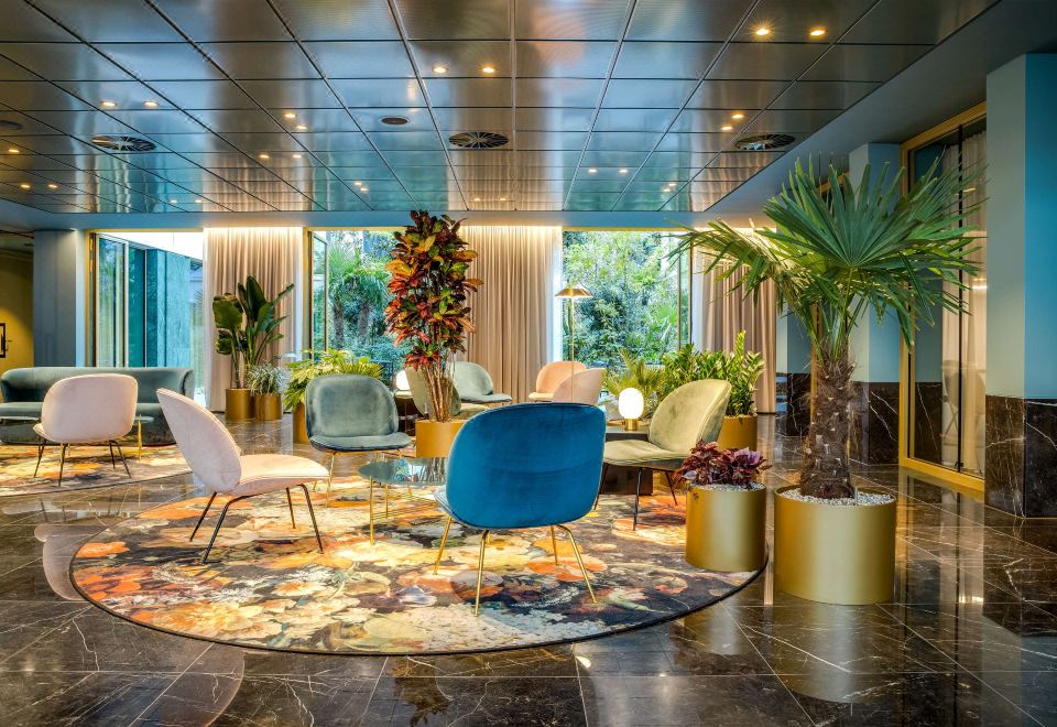 a modern hotel lobby with various seating options , including couches and chairs , as well as potted plants at NH Collection Antwerp Centre