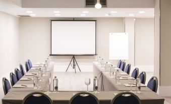 a conference room set up for a meeting , with chairs arranged in rows and a projector on the wall at Artiem Capri