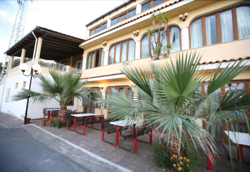a street view of a building with palm trees and tables set up on the sidewalk at Hotel All'Antico Pozzo