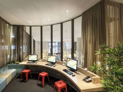 a modern office space with curved walls , large windows , and multiple computer workstations arranged in an office setting at Ibis Melbourne Hotel and Apartments