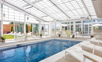 a large indoor swimming pool surrounded by lounge chairs , where people are relaxing and enjoying their time at Element Lexington