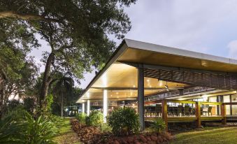 a modern building with a thatched roof , surrounded by trees and grass , at night at Albatross Bay Resort