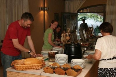 a group of people are gathered around a table filled with various food items , including bread and bowls at Valley Village