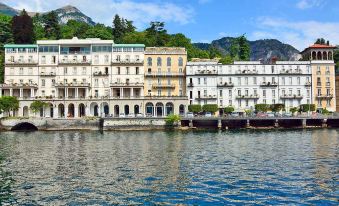 a row of buildings along the side of a body of water , possibly a lake or river at Grand Hotel Cadenabbia