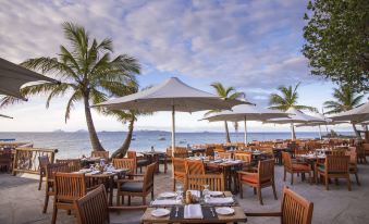 an outdoor dining area at a restaurant , with tables and chairs set up for guests to enjoy their meal at Castaway Island Fiji