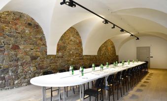 a long table with chairs is set up in a room with stone walls and arches at Hotel Maribor & Garden Rooms