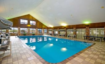 an indoor swimming pool surrounded by a hotel , with several people enjoying their time in the pool area at Best Western Tomah Hotel