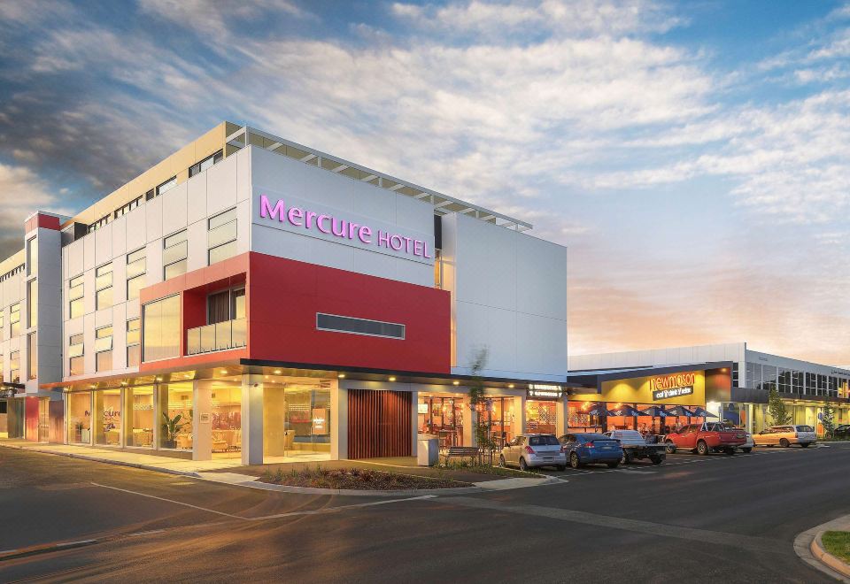 a large building with a red and white facade , located in a city setting with cars parked nearby at Mercure Warragul