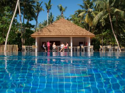 a group of people gathered around a swimming pool , enjoying their time in the sun at Vilamendhoo Island Resort & Spa