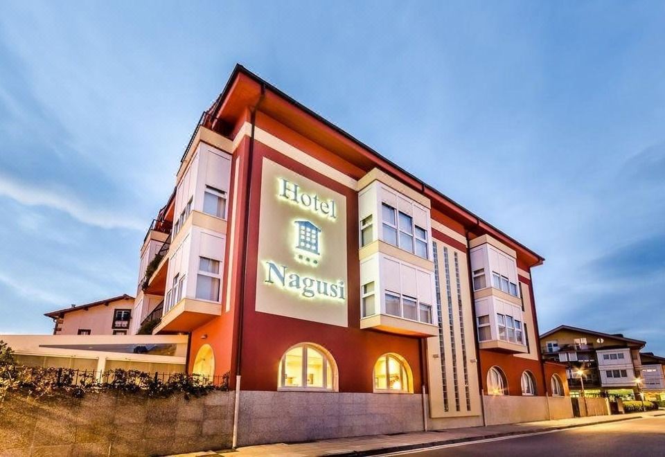 "a large building with the words "" hotel neptun "" displayed on its side , illuminated at night" at Hotel Nagusi