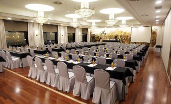 a large conference room with rows of tables and chairs , each table has a white tablecloth at Hotel Bahía