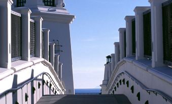 a white building with a staircase leading up to it , overlooking the ocean on a sunny day at Hyatt Regency Huntington Beach Resort and Spa