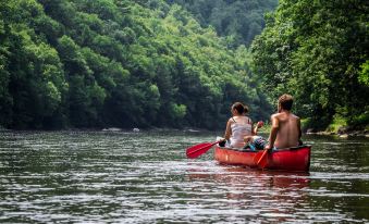 a man and a woman are paddling a red canoe on a river , surrounded by lush green trees at Ramada by Wyndham Clarion