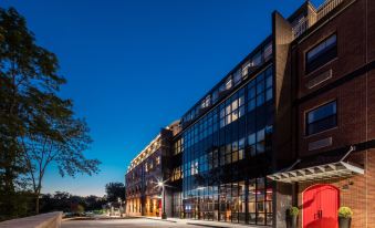 a large brick building with a red door is lit up at night , surrounded by trees at Hotel Nyack, A Joie de Vivre Hotel by Hyatt