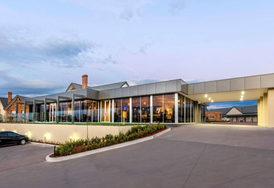 a modern building with large windows and a glass facade , situated in a parking lot at Mercure Goulburn