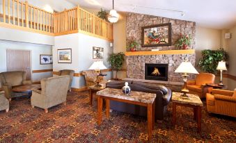 a cozy living room with a fireplace , couches , and a staircase leading to the second floor at AmericInn by Wyndham Anamosa