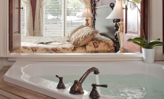 a bathroom with a bathtub and a sink , as well as a bedroom with a bed at Colonial Inn