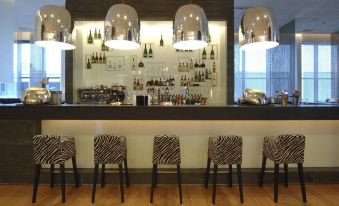 a bar area with several zebra print chairs and a bar counter stocked with various bottles at Hilton Helsinki Airport