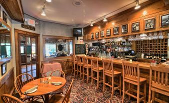 a cozy bar with wooden walls , various bottles of liquor on the counter , and a dining table in the center at Eagle Mountain House and Golf Club