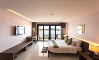 a large bed with white linens and green accents is in a room with a sliding glass door leading to a balcony at Siam Triangle Hotel