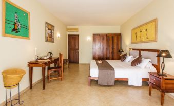 a well - decorated hotel room with a bed , desk , and chair , as well as a door leading to another room at VOI Amarina Resort