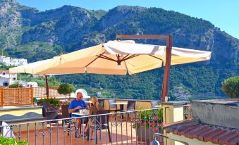 a man is sitting at a table under an umbrella on a patio overlooking mountains at Villa Maria