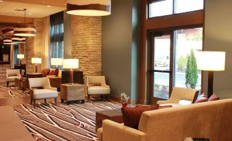 a well - lit hotel lobby with various seating options , including couches , chairs , and a coffee table at Angel of the Winds Casino Resort