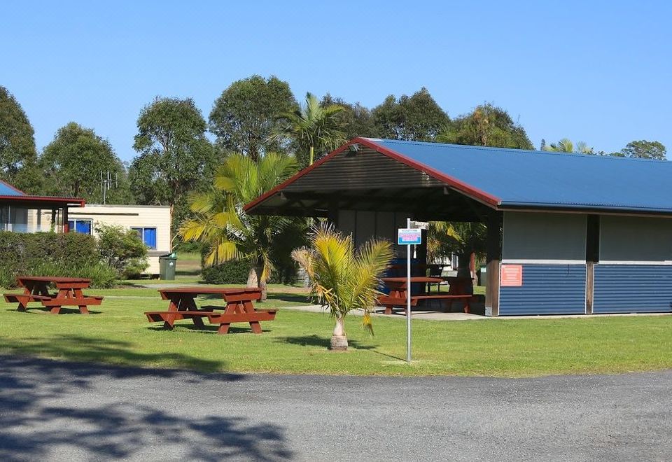 a small , well - maintained park with a picnic area and a building , surrounded by green grass at Stoney Park