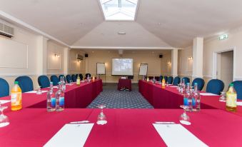a conference room set up for a meeting , with several chairs arranged in a semicircle around a table at Best Western New Holmwood Hotel