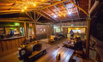 a group of people sitting around wooden tables in a room with exposed wood beams and brick walls at La Tigra Rainforest Lodge