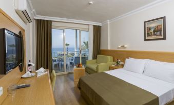 a hotel room with a large bed , a green chair , and a balcony overlooking the ocean at Senza Grand Santana Hotel