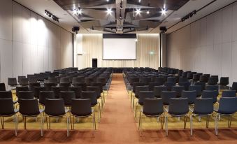 a large conference room with rows of black chairs arranged in front of a projector screen at Hyatt Place Melbourne Essendon Fields