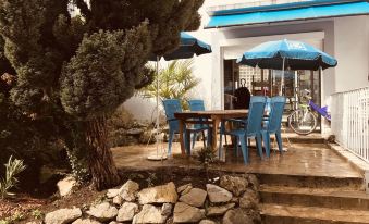 a blue and white house with a patio area featuring a dining table , chairs , and an umbrella at Myosotis