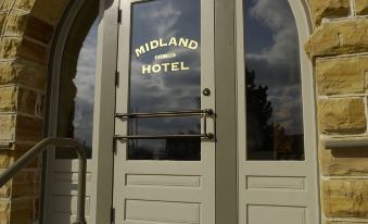 the entrance to the midland hotel is shown with a large glass door and stone steps leading up to it at Midland Railroad Hotel
