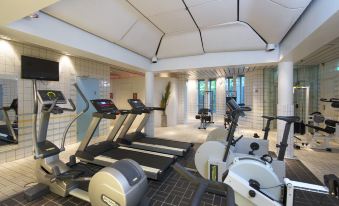 a gym with multiple exercise equipment , including treadmills and stationary bikes , set up in an indoor space at Thon Hotel Oslofjord