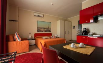 a modern bedroom with a red bed , orange chair , and matching curtains , along with a dining table and kitchen area at Easy Space