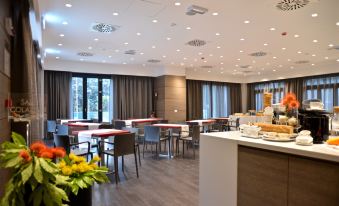 a large dining area with multiple tables and chairs , some of which are occupied by people at Hotel Forum