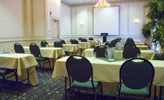 a conference room with tables and chairs set up for a meeting , with a projector screen in the background at Best Western Plus Chelmsford Inn