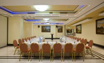 a conference room with a long table and chairs , water bottles , and paintings on the walls at Semeli Hotel