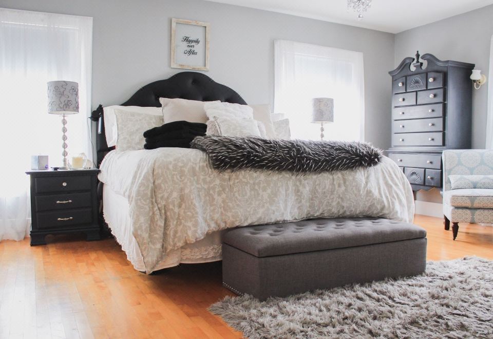 a modern bedroom with white walls , black headboard , wooden floors , and gray fur rug , as well as a bed with black headboard at Taylor Edes Inn