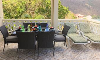 a dining table with chairs and a bottle of wine is set up on a patio overlooking mountains at Ocean View Villas