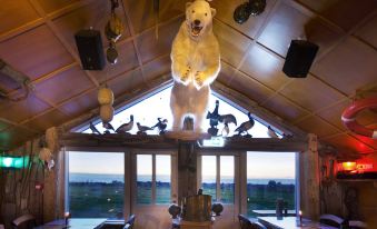 a dining room with a large polar bear statue on the wall , surrounded by tables and chairs at Hlid Fisherman's Village