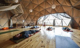a group of people are laying on the floor in a room with wooden floors and large windows at Ecocamp Patagonia