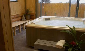 a large hot tub is surrounded by wooden walls and has a bench next to it at Shining Star Beachfront Accommodation