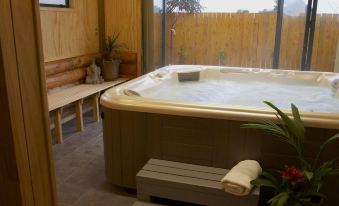 a wooden room with a large bathtub and a bench , surrounded by wooden walls and a fence at Shining Star Beachfront Accommodation