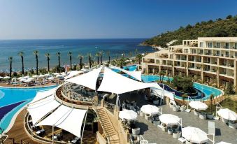 a large resort with a pool surrounded by umbrellas and tables , overlooking the ocean in the background at Paloma Pasha