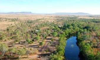 an aerial view of a forested area with a river running through it , surrounded by dry grass and trees at Parry Creek Farm Tourist Resort & Caravan Park